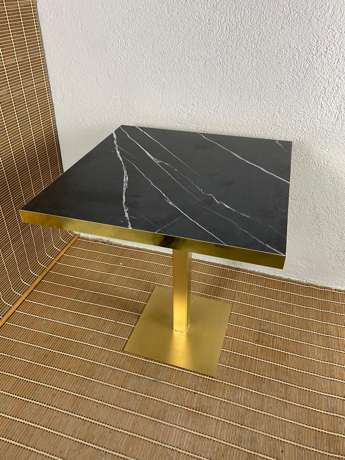 mesa estilo mármol negro con canto de metal dorado y pie de hierro dorado