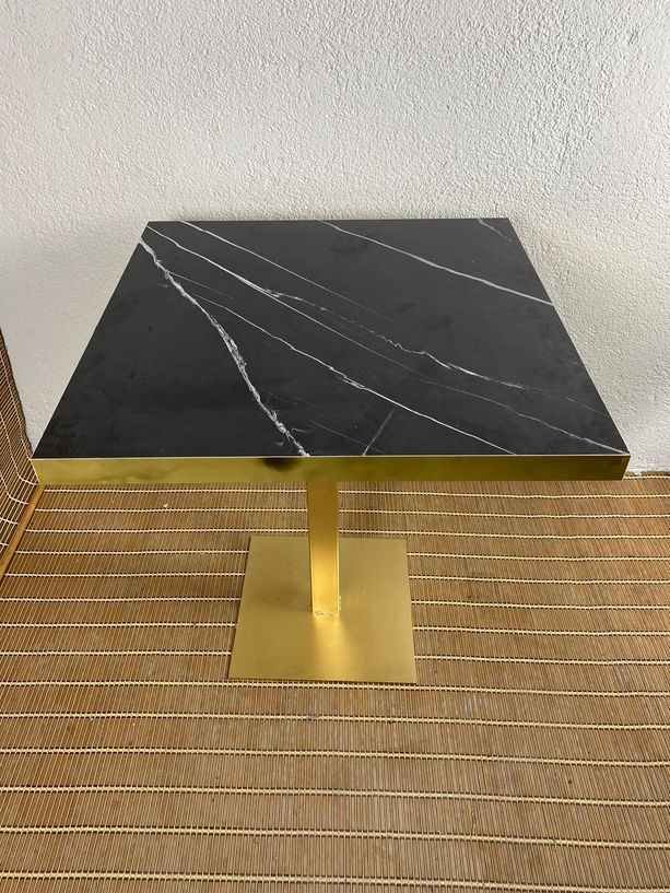 mesa estilo mármol negro con canto de metal dorado y pie de hierro dorado