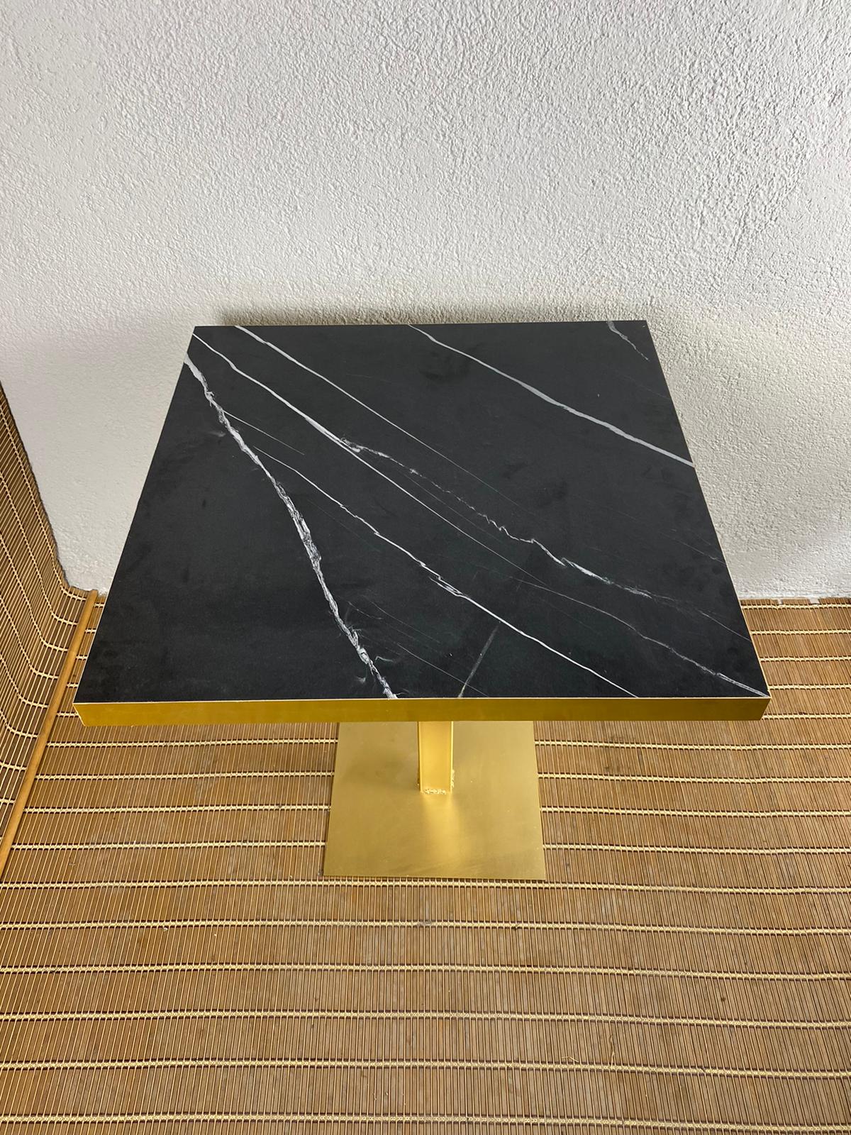 mesa estilo mármol negro con canto de metal dorado y pie de hierro dorado